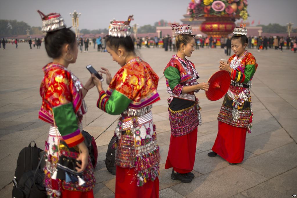 在美国总统唐纳德&middot;川普将对中国首都进行为期三天的国事访问前夕，在北京天安门广场，穿着少数民族服装的女子照相，看着智能手机（2017年11月6日）。这是自发的游客还是当局安排的呢？